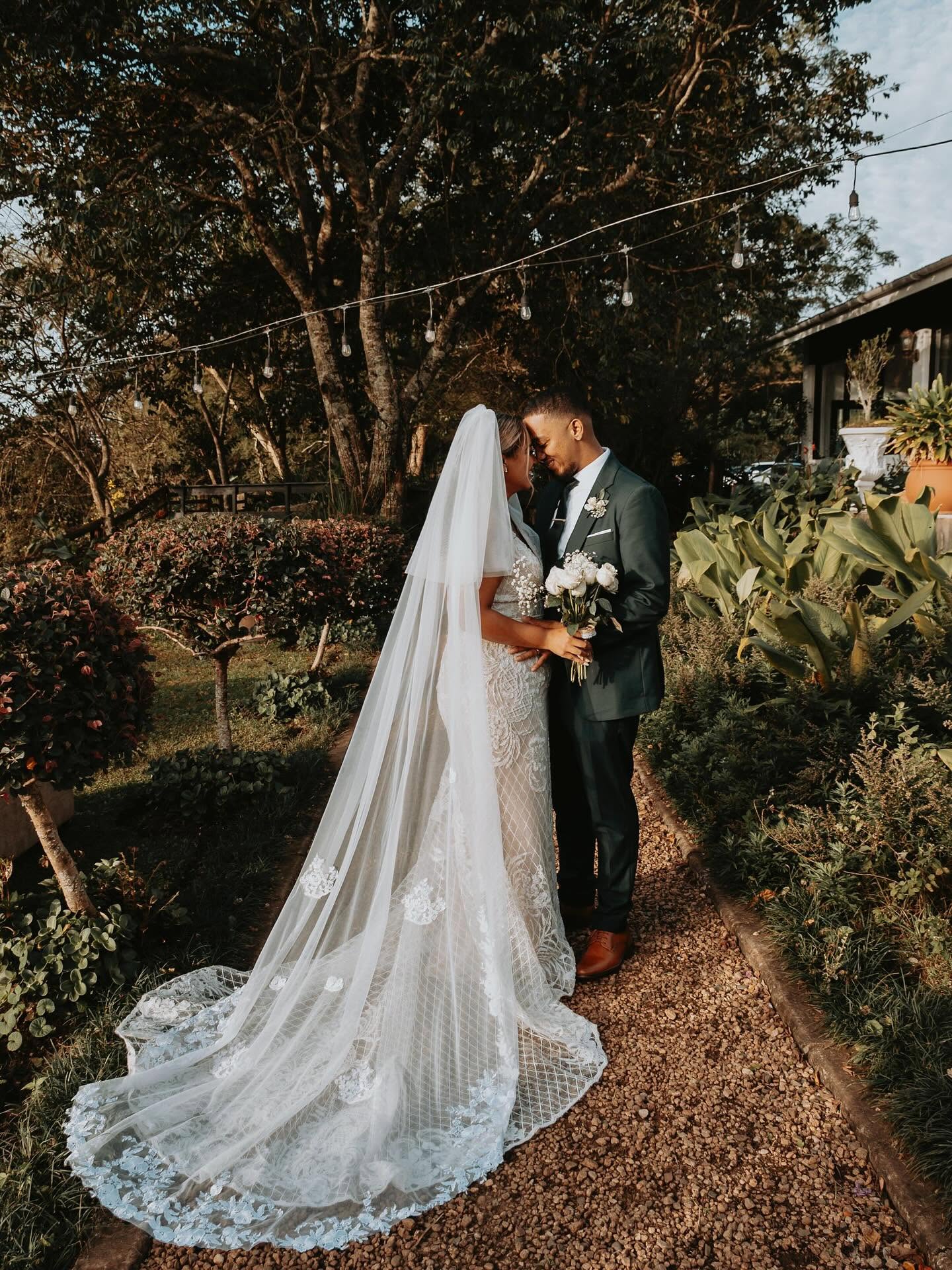 A couple on the garden path at golden hour beneath string lights