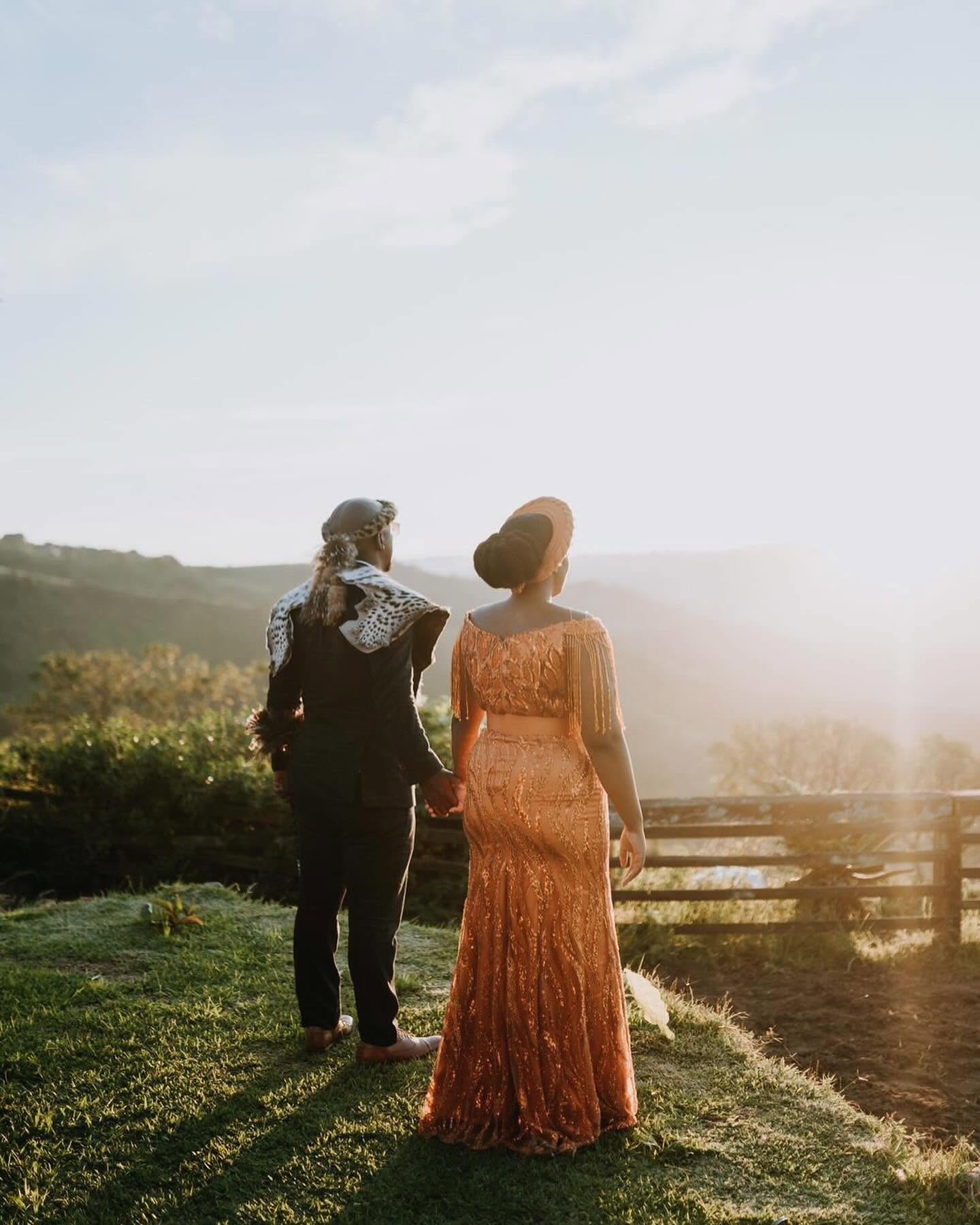 A couple in traditional dress looking out over the hills at golden hour