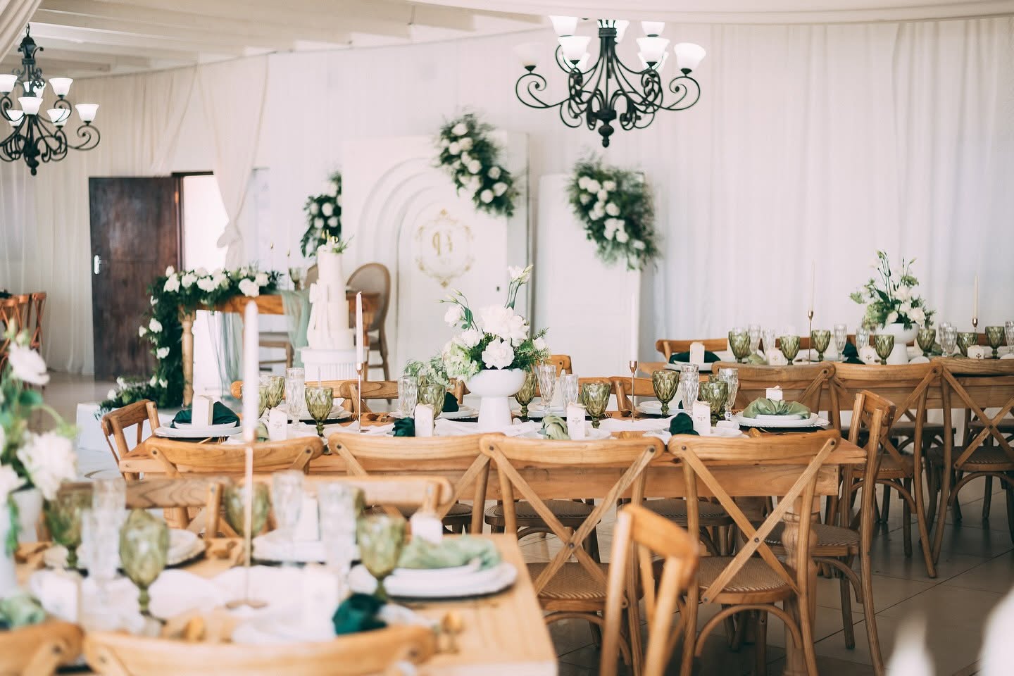 Indoor marquee with chandeliers, timber tables and green glassware