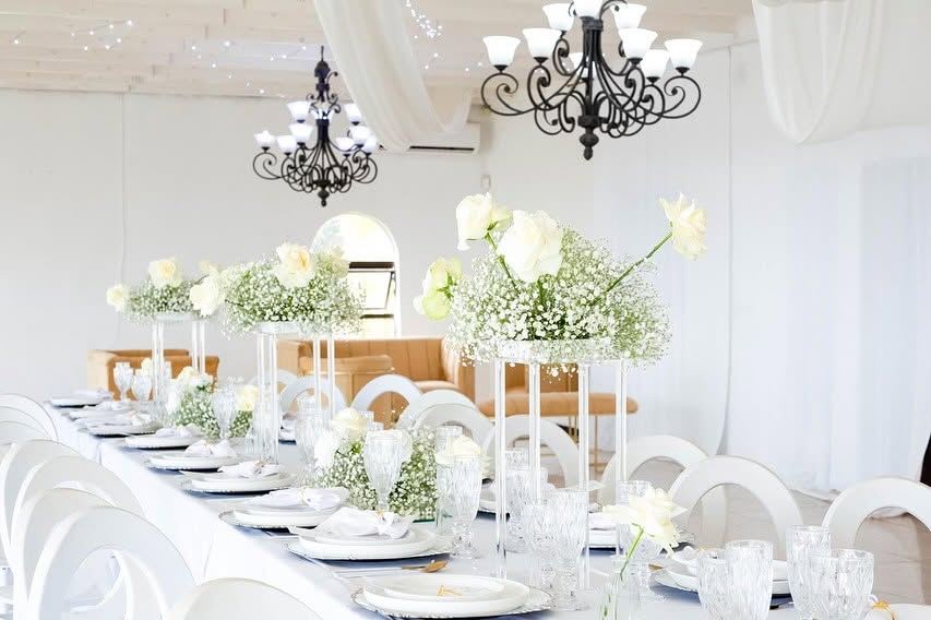 White hall with chandeliers and tall baby's breath centrepieces
