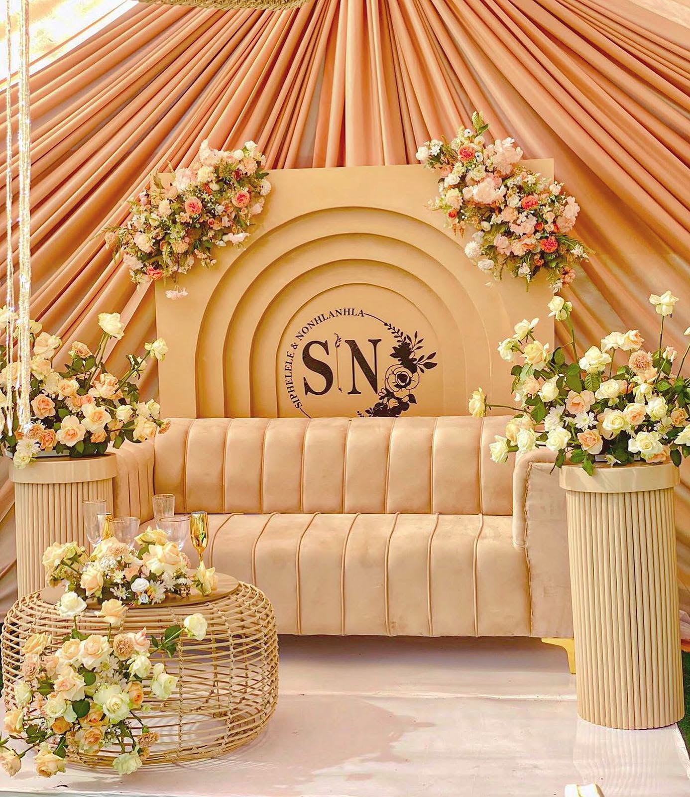 Peach draped lounge setting with roses and a monogram backdrop