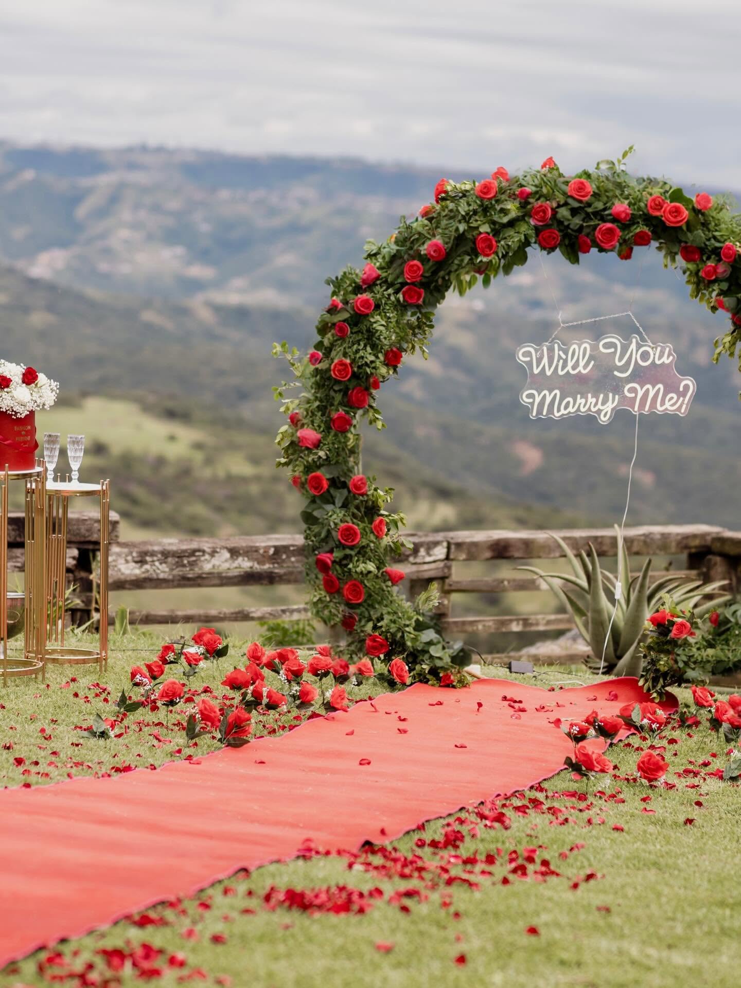 Red rose arch and petal aisle set for a proposal above the valley