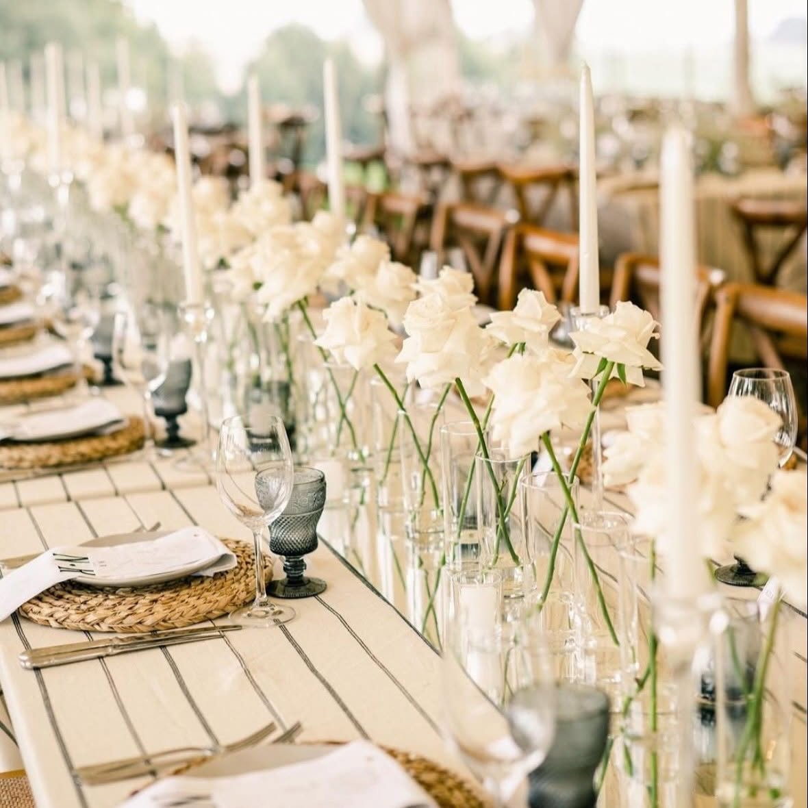 Single-stem white roses and tapered candles along a linen table